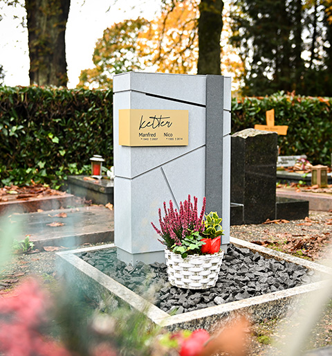Nahaufnahme von einem Einwurfschlitz im Grabstein
